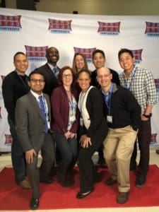 Group of nine people smiling at the Best Ever Conference, standing on a red carpet in front of a branded backdrop.