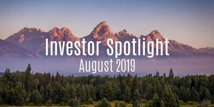 Mountain landscape with trees in the foreground and a text overlay reading "Investor Spotlight August 2019," highlighting opportunities in land development.