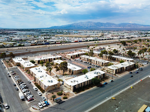 Aerial view of a sprawling industrial area with warehouses bustling from recent purchases, surrounded by winding roads and distant mountains under a cloudy sky.